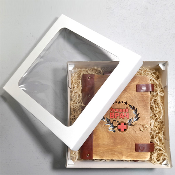 Подарочный набор для врача блокнот формата А5 в кожаном переплете с гравировкой «Лучший врач» в подарочной коробке из белого картона с прозрачным верхом и деревянной ручкой с рисунком-гравировкой Подарочный набор для врача блокнот формата А5 в кожаном переплете с гравировкой «Лучший врач» в подарочной коробке из белого картона с прозрачным верхом и деревянной ручкой с рисунком-гравировкой